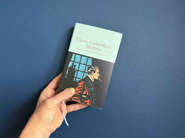 Cover of the Macmillan Collectors edition hardback of the Locked Room Mysteries held by my hand against a navy background.